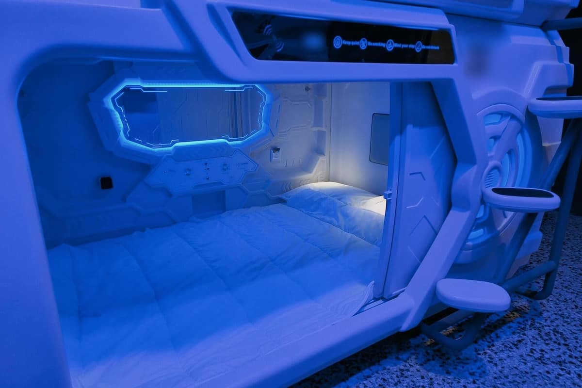 Una habitación futurista con una cama, un panel de control y una zona de estar.
