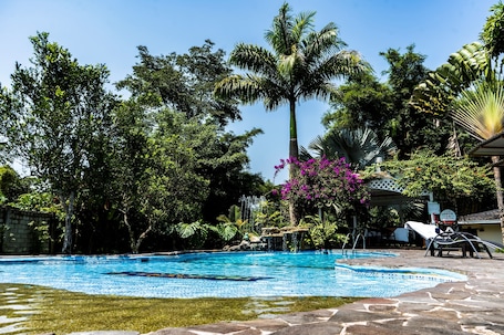 Una piscina al aire libre, sillones reclinables de piscina