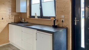 A kitchen with a countertop, cabinets, a window with blinds, and a door. - Pet friendly home in Jantar with sauna (Jantar)