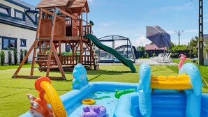 An inflatable pool with various toys and a wooden play structure in the background. - Pet friendly home in Jantar with sauna (Jantar)