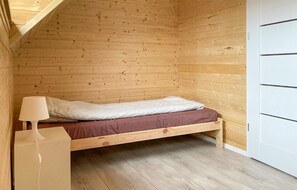 A small wooden room with a single bed, a nightstand, and a white door. - Pet friendly home in Jantar with sauna (Jantar)