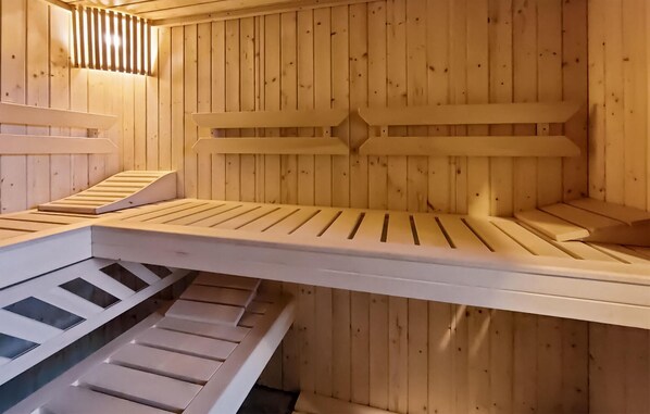 A sauna with wooden benches and a sloped floor design.