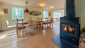 Una habitación con piso de madera, una mesa de comedor con sillas, una chimenea y obras de arte en las paredes.