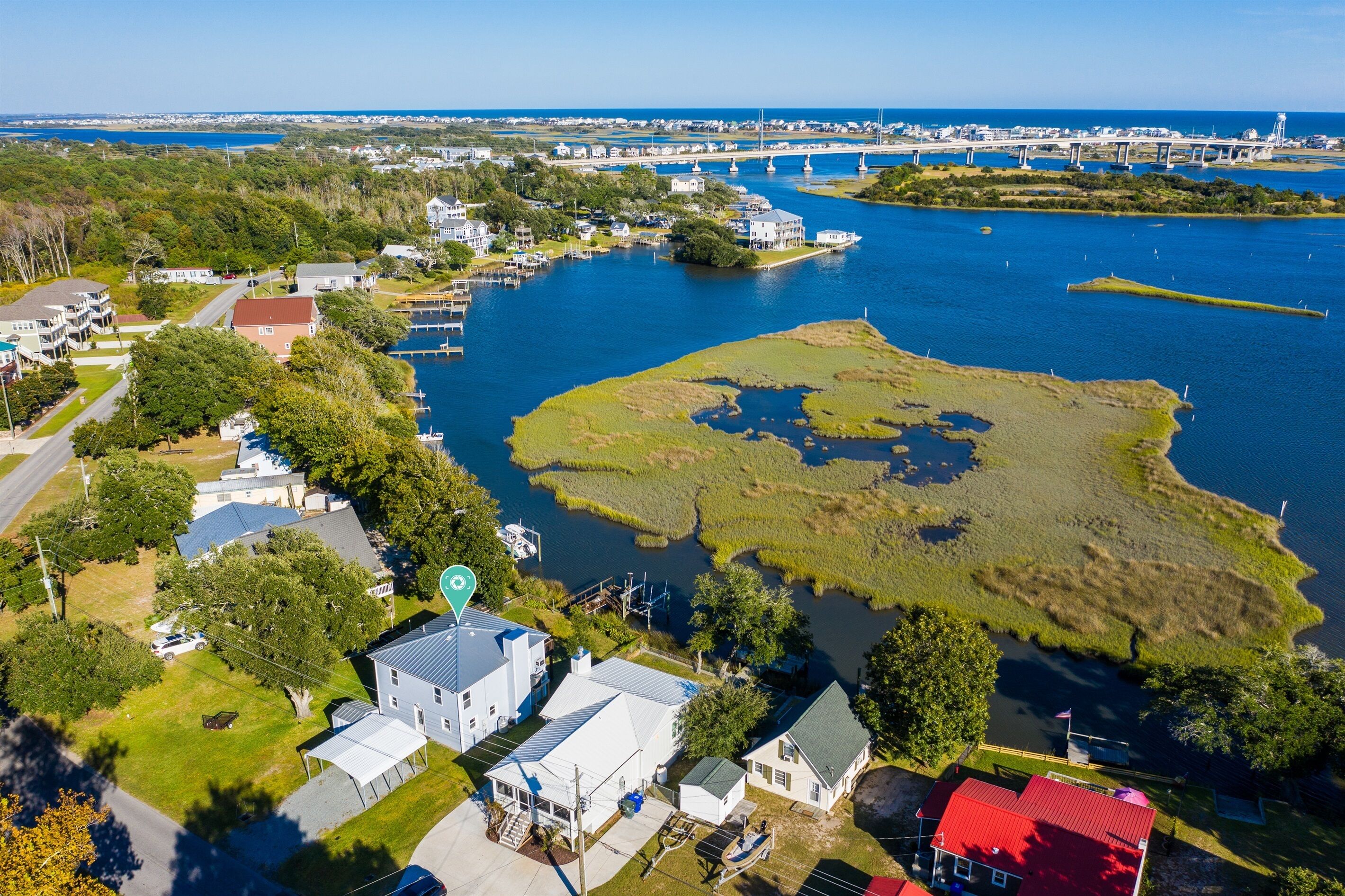 Une vue aérienne d’une ville côtière, avec des maisons, un port de plaisance et un pont en arrière-plan.