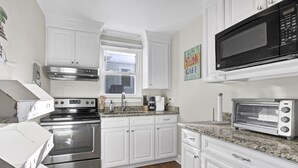 A modern kitchen with white cabinets, stainless steel appliances, and a granite countertop. - A Turtle's View-Waterfront-Dock-Fenced Yard-Dog Friendly (Surf City)