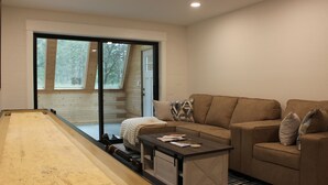 A modern living room with a beige sofa, a coffee table, and a billiards table. - Bandon Country Club (Bandon)