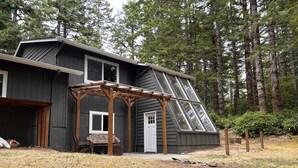 A house with a sloped roof, a covered porch, and a stone marker in the yard. - Bandon Country Club (Bandon)