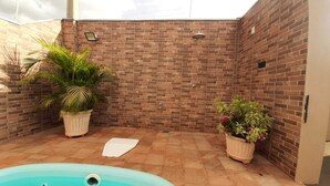Un espacio exterior pequeño y cercado con pared de ladrillo, una piscina y plantas en macetas.