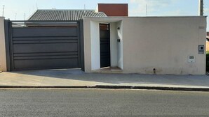 Un garaje con una puerta negra y un pequeño acceso abierto que conduce a un edificio de pared blanca y tejado rojo.
