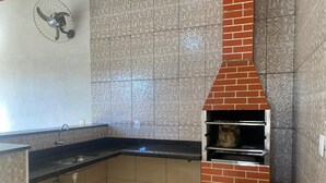Una cocina con horno de ladrillo integrado, un lavabo y un ventilador.