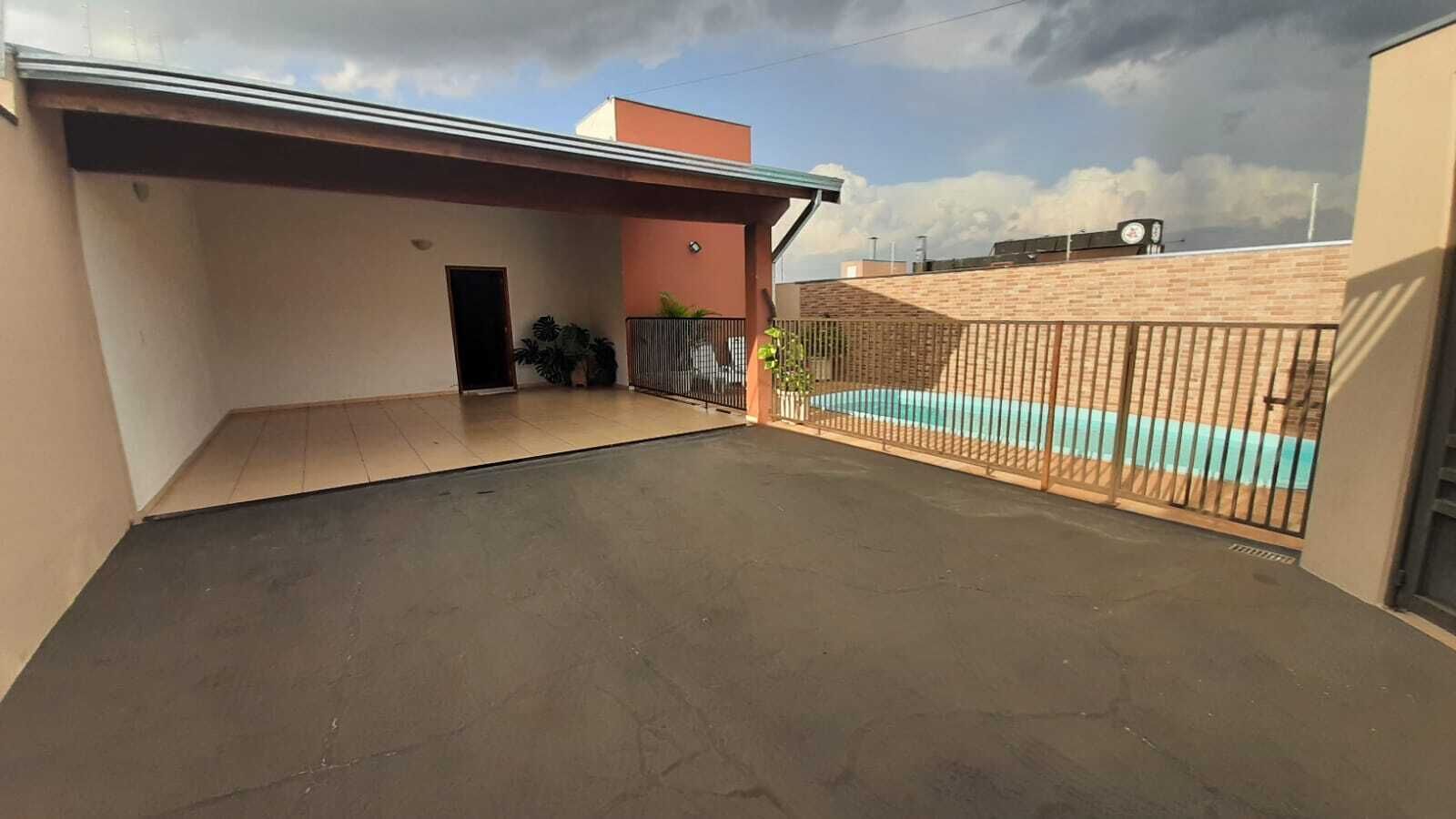 A spacious outdoor area with a swimming pool, a covered patio, and a brick wall.