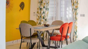 A dining area with a table and chairs, a yellow wall, and patterned curtains.