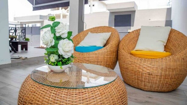 A wicker lounge area with a glass table and two wicker chairs, one with a blue cushion and the other with a yellow cushion.