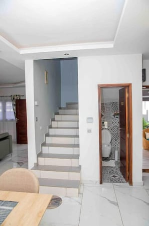 Stairs lead to an upper level, with a bathroom and seating area below.