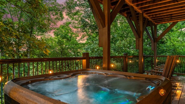 A hot tub under a wooden pergola with a view of trees and a pink sky. - Brand New Near PF~Royal Ridge~Indoor Pool-Racing Games (Sevierville)