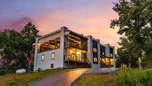 A modern building with a stone facade, large windows, and a balcony with string lights. - Brand New Near PF~Royal Ridge~Indoor Pool-Racing Games (Sevierville)