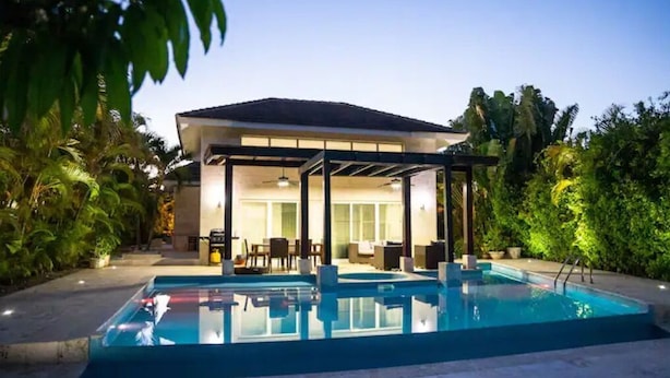 A modern house with a swimming pool, outdoor seating, and lush greenery.