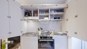 A modern kitchen with built-in appliances, open shelving, and a compact layout.