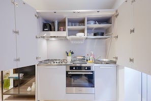 A modern kitchen with built-in appliances, open shelving, and a compact layout.