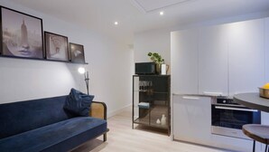 A modern living space with a sofa, a glass cabinet, and a kitchen area with cabinets and an oven.