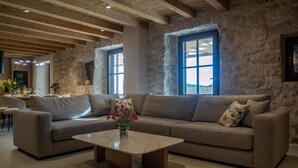 A spacious living room with a stone wall, a sofa set, a coffee table, and a dining area in the background. - Amazing home in Gruda (Gruda)