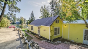 A yellow building with a metal roof, a wooden deck, and a stone pathway leading to a dock. - Newport Cabin on Diamond Lake w/ Private Boat Dock (Newport)