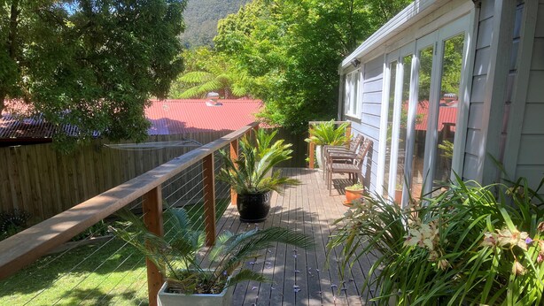 A wooden deck with potted plants and a wooden railing. - Historic Cottage 4 Riverside Dve. Pet friendly, flat fenced yard  on the River. (Warburton)