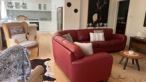 A modern living room with a red sofa, a wicker chair, and a cowhide rug. - Historic Cottage 4 Riverside Dve. Pet friendly, flat fenced yard  on the River. (Warburton)