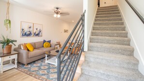 Una sala de estar con sofá, mesa de centro y una escalera.