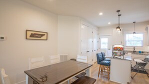 Una cocina moderna con armarios blancos, una mesa de comedor de madera y una zona de bar.