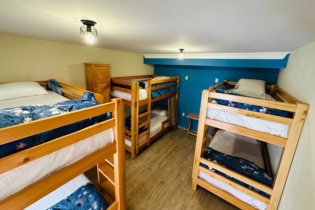 Une chambre de dortoir avec des lits superposés, une armoire en bois et un luminaire au plafond.