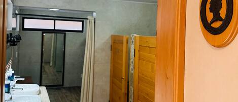 Un baño con tres lavamanos, suelo de madera y zona de ducha.