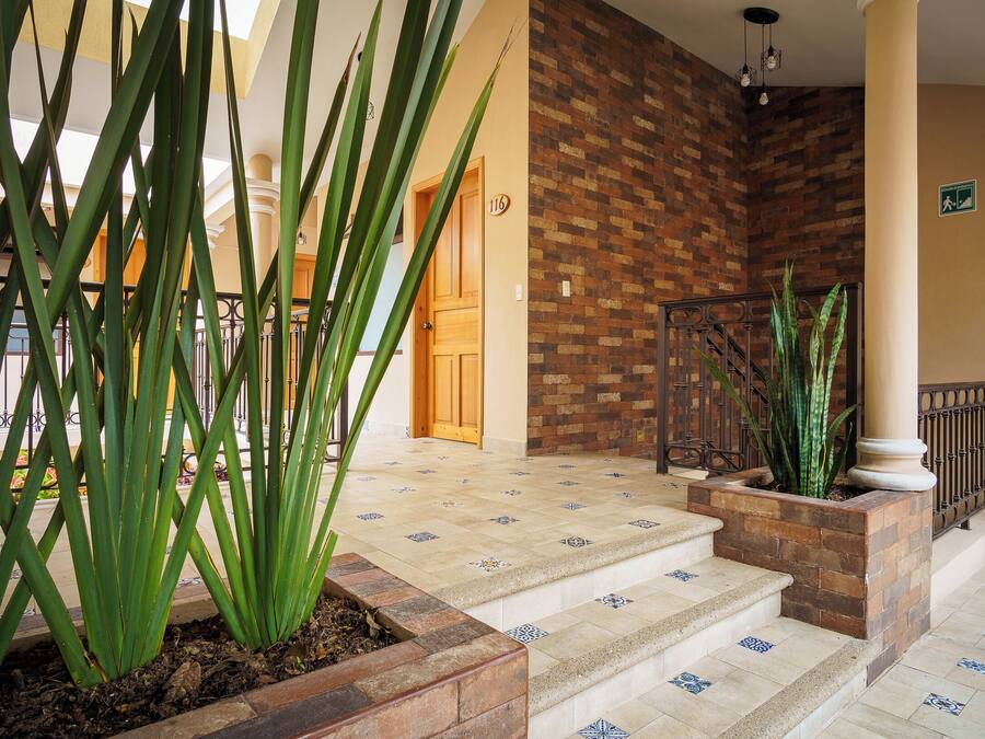 Un vestíbulo de hotel con una escalera, una pared de ladrillo y una planta en maceta.