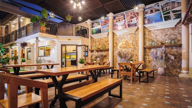 A restaurant with wooden benches and tables, a balcony, and a decorative wall with pictures. - Tierra Alta Hostal (San Cristóbal de las Casas)