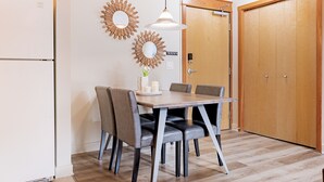 A dining area with a wooden table, four chairs, a hanging pendant light, and two wall mirrors. - Cozy 2 Bedroom/3 Beds/Mountain View /AC/Free Parking (Canmore)