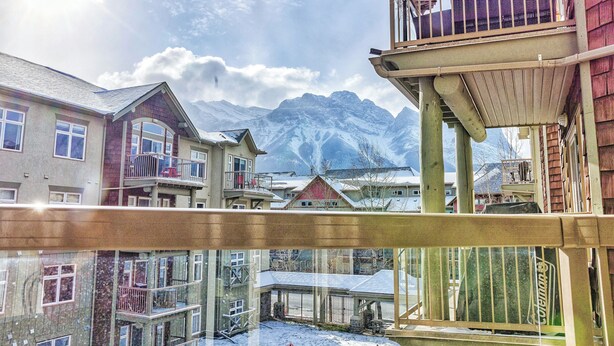 A residential area with multi-story buildings, balconies, and a snowy mountain backdrop. - Cozy 2 Bedroom/3 Beds/Mountain View /AC/Free Parking (Canmore)