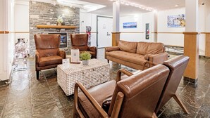 A lobby with leather chairs, a sofa, a stone fireplace, and a tiled floor. - Cozy 2 Bedroom/3 Beds/Mountain View /AC/Free Parking (Canmore)