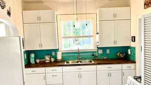 A kitchen with white cabinets, a window with blinds, a sink, and a stove. - Upstairs @ Courthouse Square - Quirky (Hot Springs)