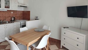 A compact kitchen with white cabinets, a stove, and a single wall-mounted TV. - Holiday apartment Rubi 3, a beautiful apartment with an enchanting view of the sea (Primošten)
