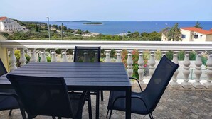 Ein Balkon mit Tisch und Stühlen mit Blick auf die Küste.