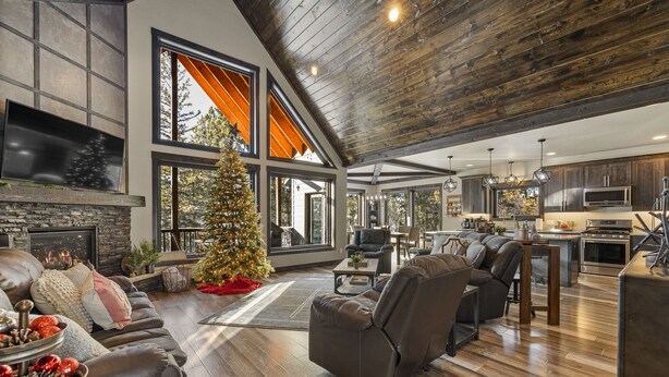 Ein geräumiges Wohnzimmer mit Kamin, Weihnachtsbaum und moderner Küche im Hintergrund.