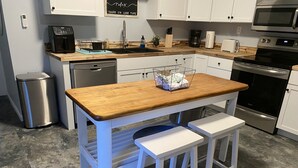A kitchen with white cabinets, a wooden countertop, a coffee maker, a toaster, and a dishwasher.