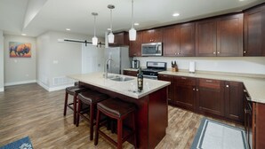 A modern kitchen with dark wood cabinets, a large island with stools, stainless steel appliances, and pendant lighting. - Mountain Views, Single family home near airport. Skyview Retreat! (Belgrade)