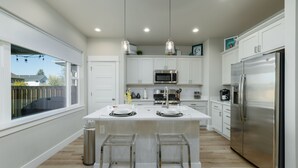A modern kitchen with white cabinets, stainless steel appliances, and a central island with stools. - Dog Friendly Townhouse, minutes to MSU & Downtown Bozeman! Welcome Home! (Bozeman)