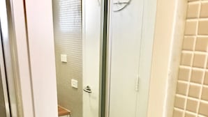 Un baño con mampara de vidrio, un lavamanos blanco y piso de baldosas.