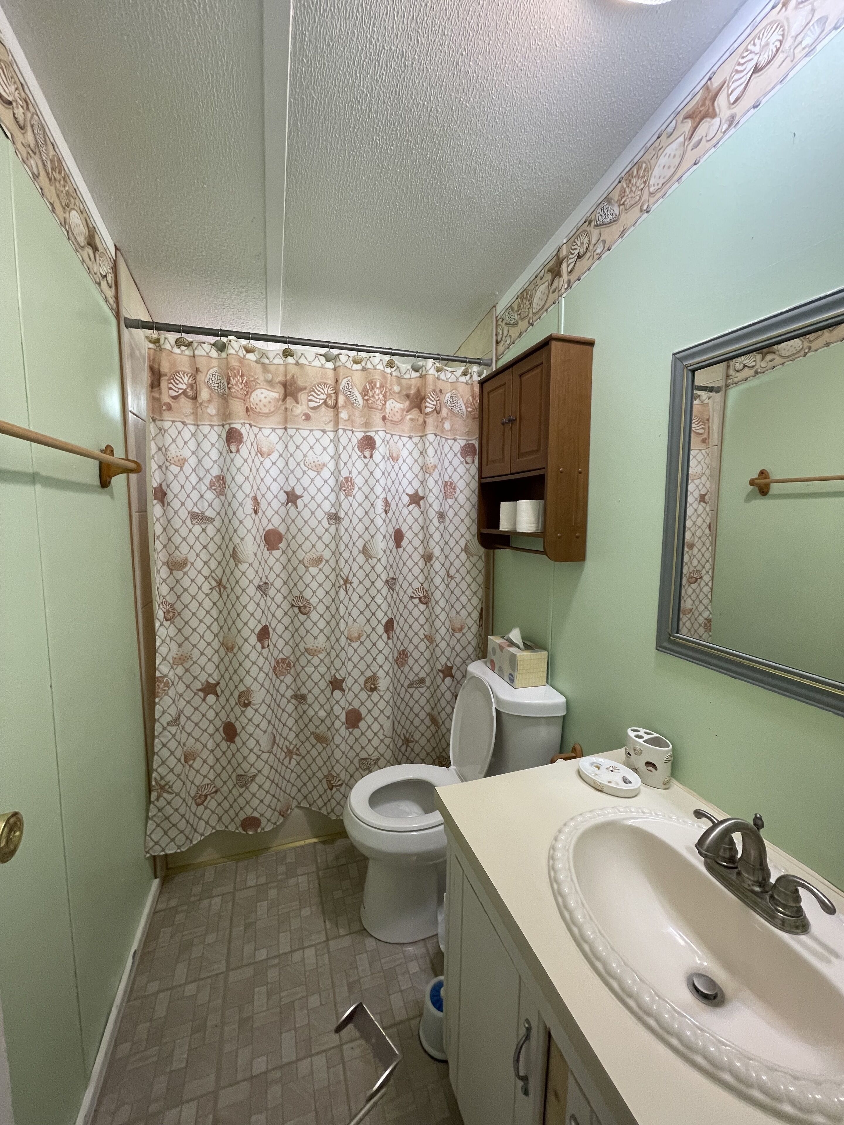Een badkamer met toilet, wastafel en douchegordijn.