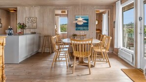 Un interior de madera con comedor, cocina y ventanas amplias.