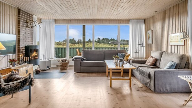 Amplia sala de estar con chimenea, ventanas grandes y vistas al exterior.