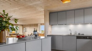 Una cocina moderna con armarios grises, techo de madera y una isla grande con un jarrón de flores.