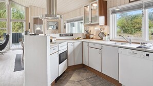 Een moderne keuken met witte kasten, een Bosch vaatwasser en een groot raam met uitzicht op de omgeving.